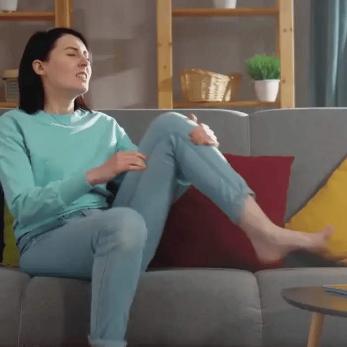 Woman experiencing foot pain before using EMS foot massager to relieve discomfort and improve circulation. Demonstrating how the best EMS foot massager works.